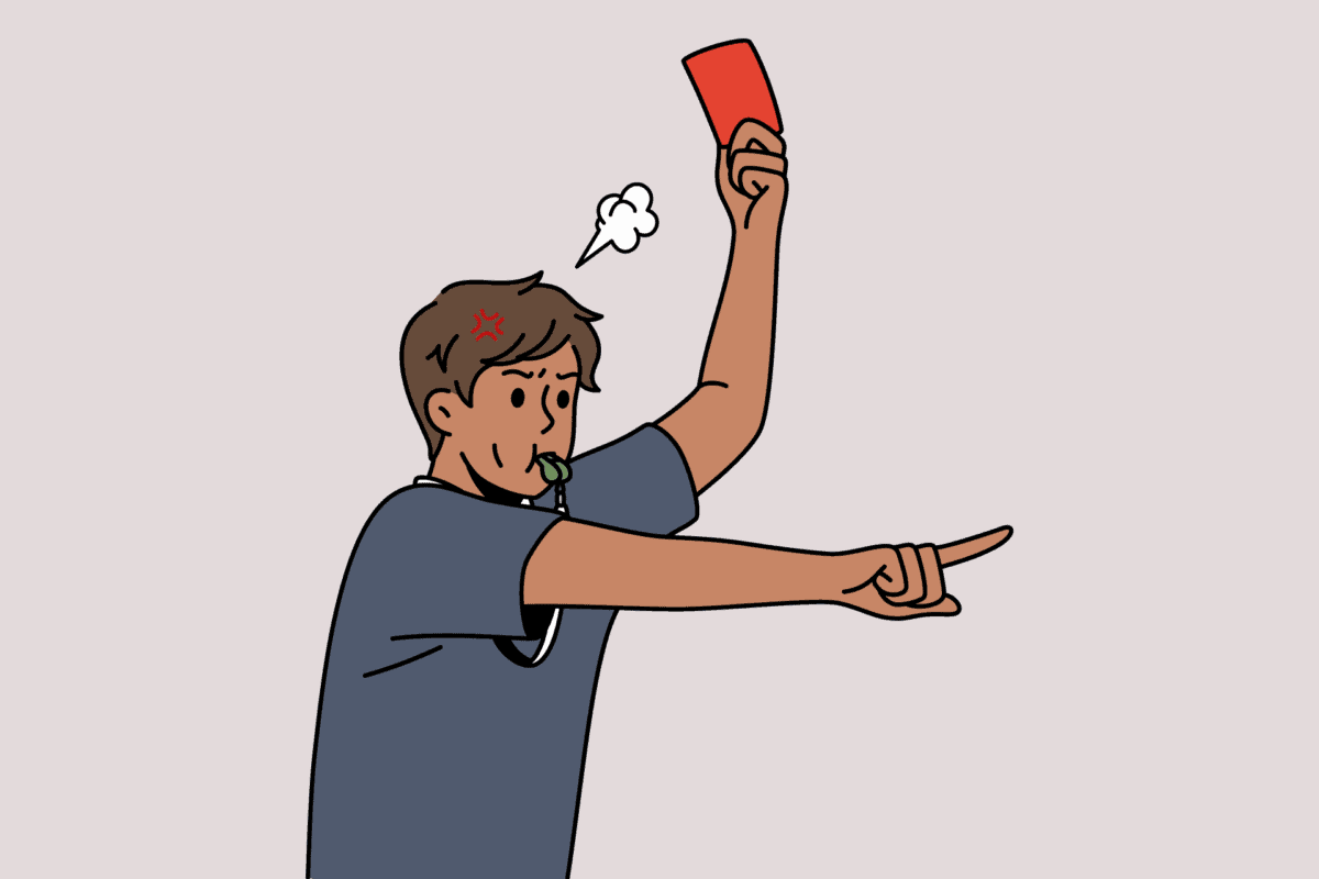 Referee holding up a red card while blowing whistle