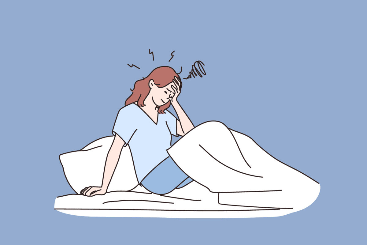 Woman sits in bed with headache
